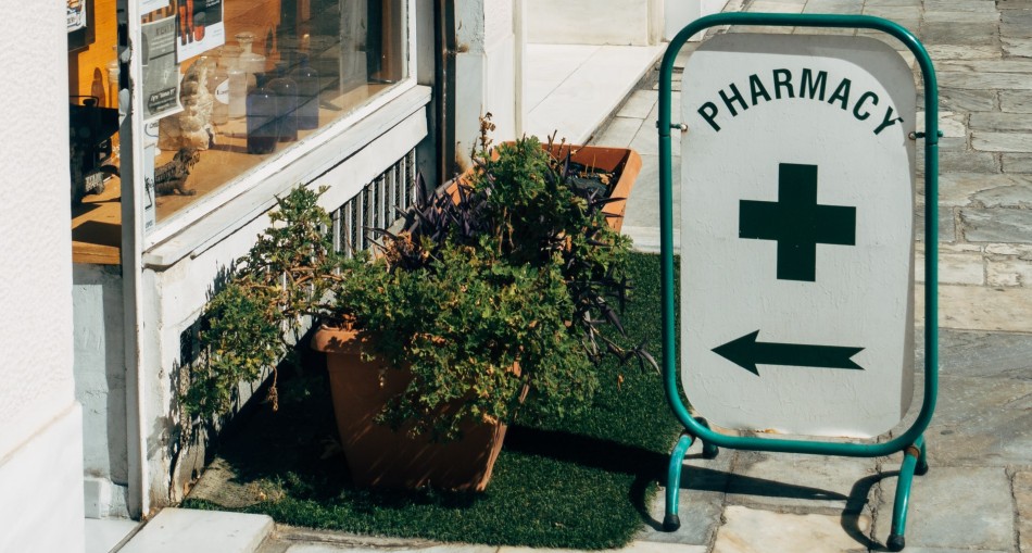 Sign post pointing to pharmacy outside a shop