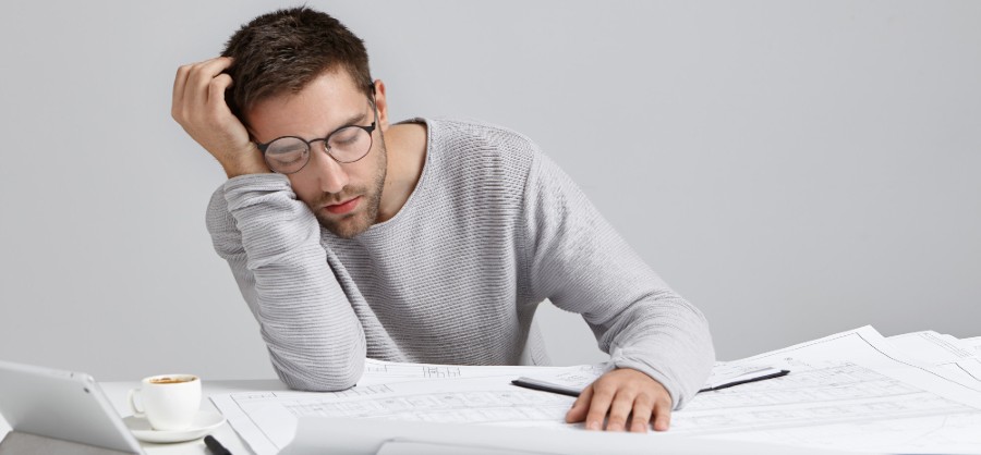 Tired man falls asleep at desk while working