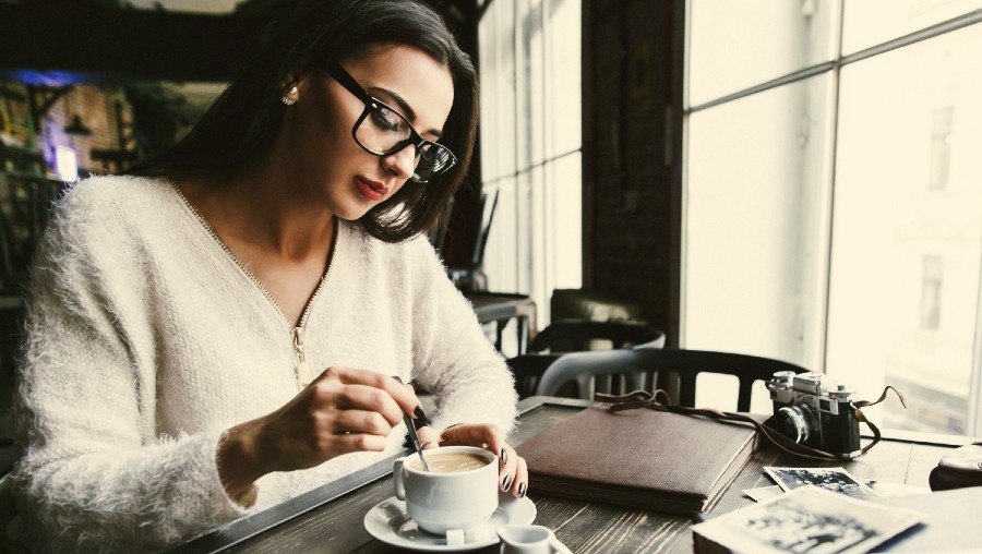 Photographer relaxing in coffee shop stirring her drink